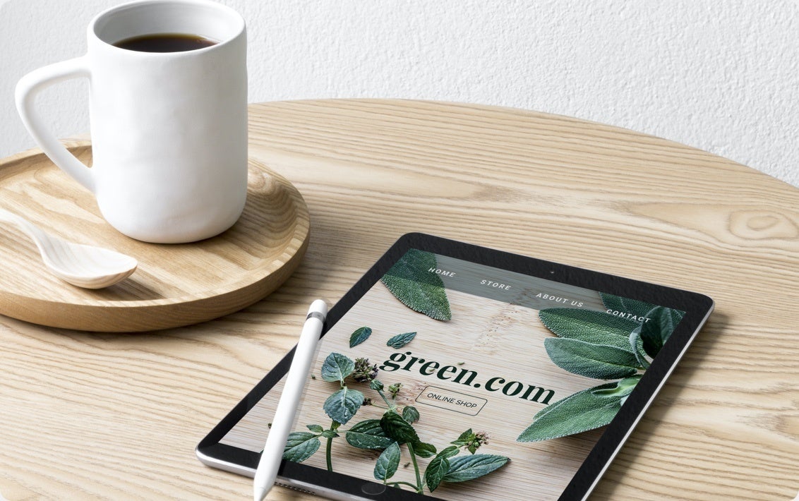 Eine Tasse Kaffee steht neben einem Tablet, auf dem eine mit Jimdo erstellte Gärtner-Website zu sehen ist.
